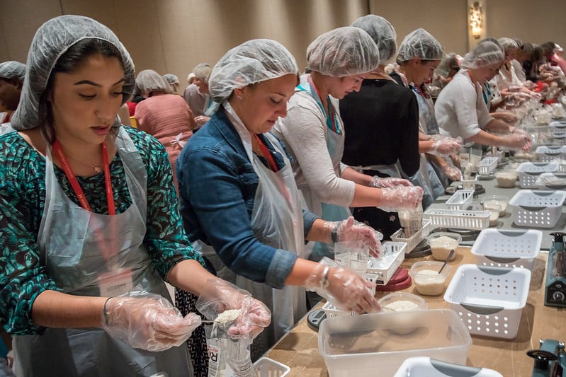 A line of people put together food packets during a group activity
