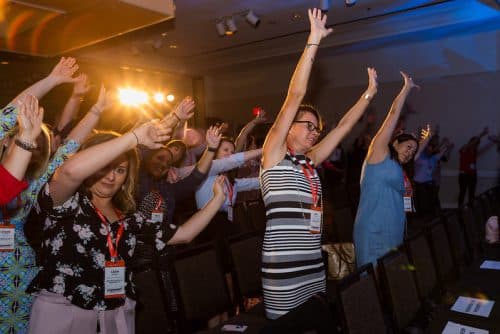 Event attendees standing and stretching at their seats