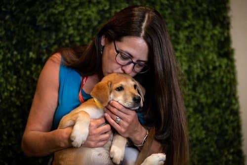 An event attendee holding a puppy and kissing the top of its head