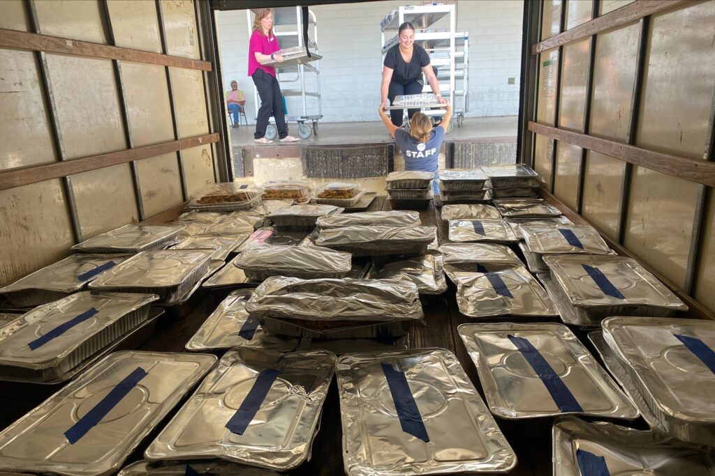 Event staff load unused meals onto a truck to be donated