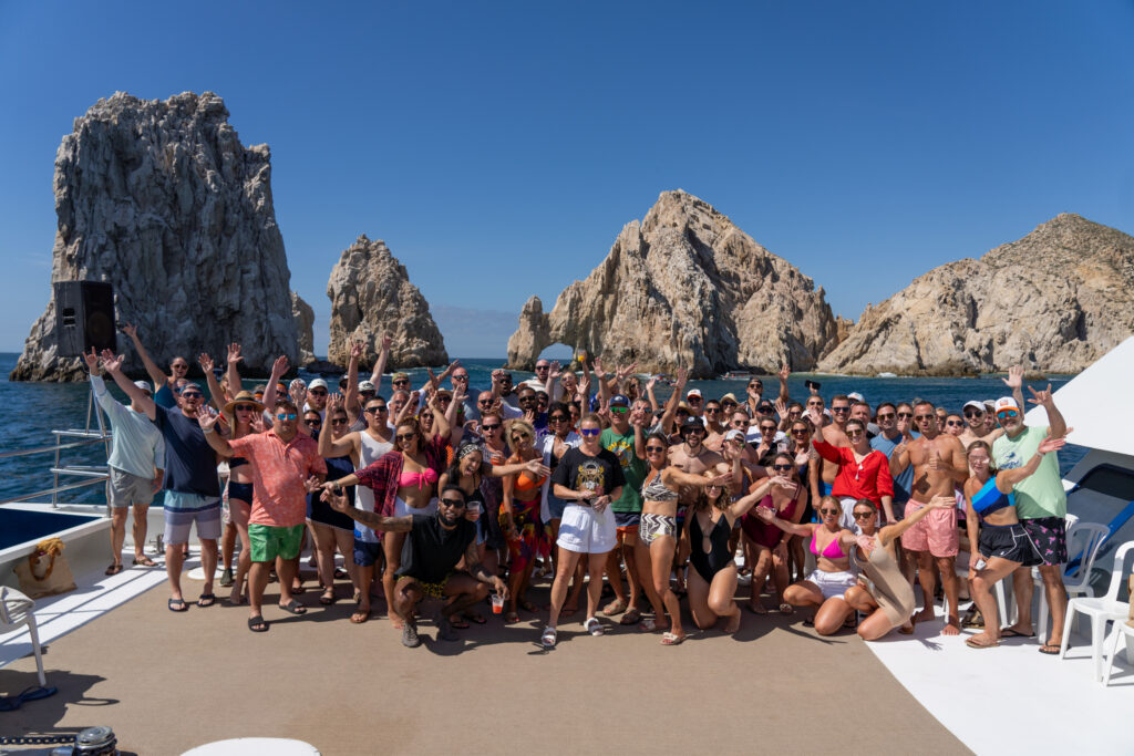 A large incentive travel group smiling and posing on a boat in Cabo San Lucas