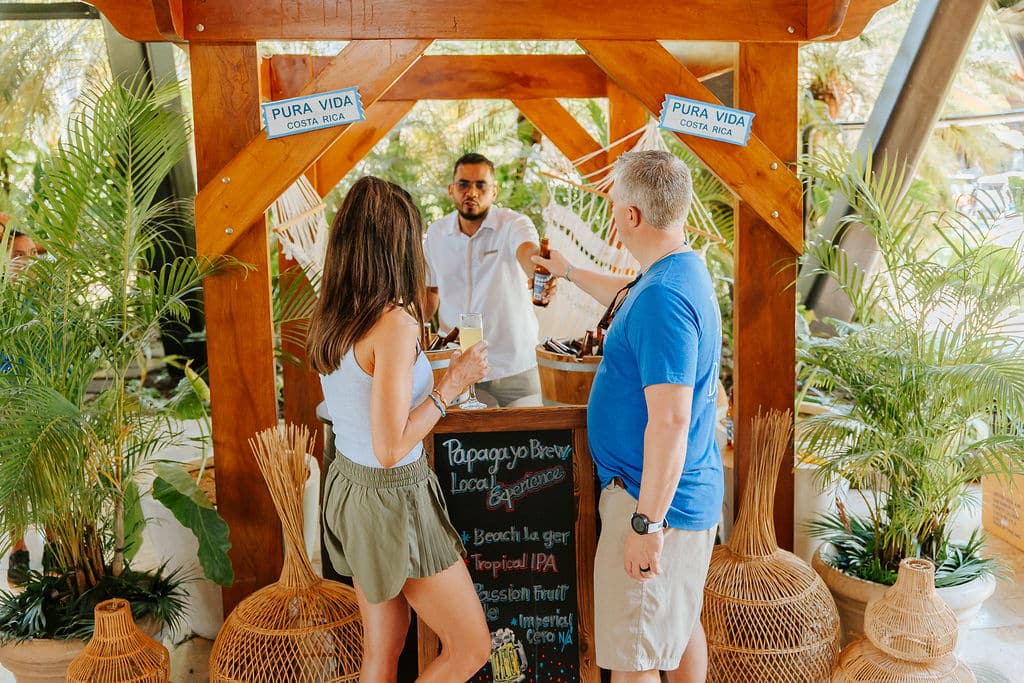 A woman and man at a small wooden bar surrounded by greenery in Costa Rica