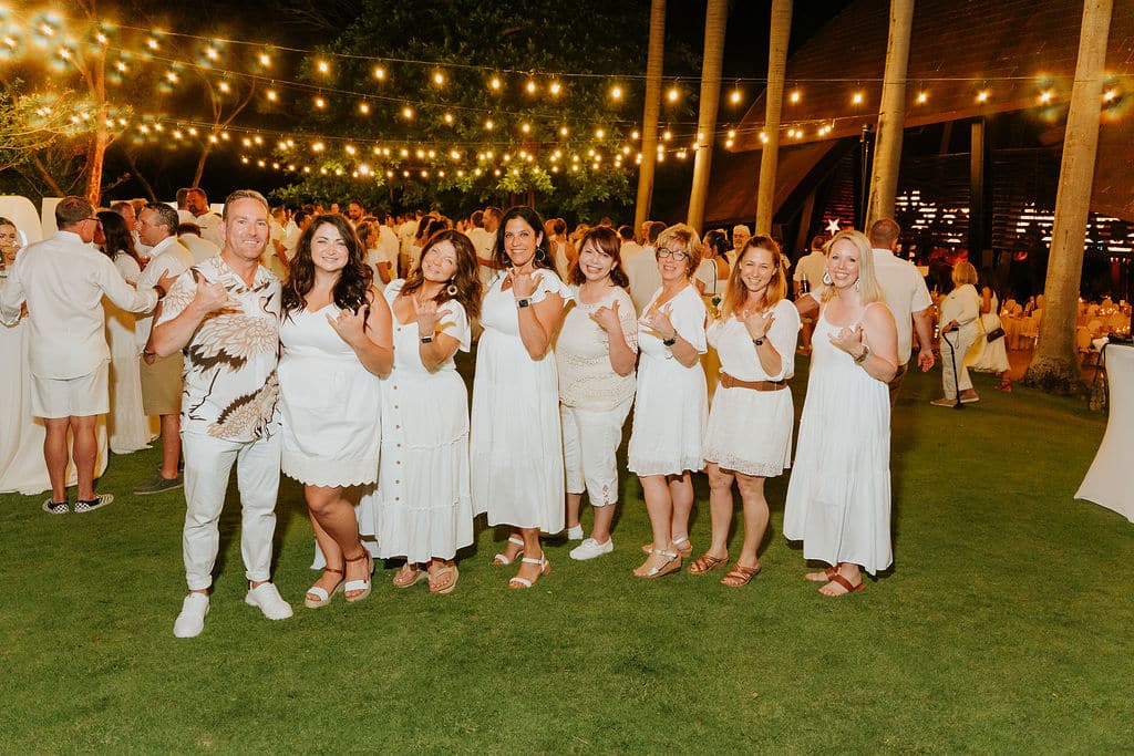 Attendees at a group incentive event wearing all white and posing for the camera