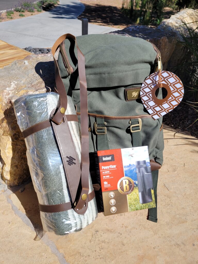 Binoculars, blanket, and other hiking gear gifted in a backpack