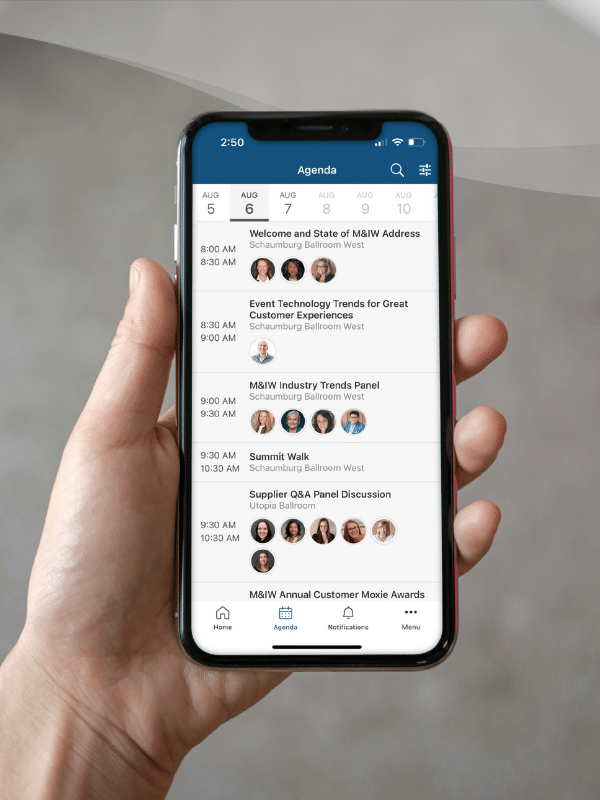 A hand holds a cell phone with an event agenda shown onscreen