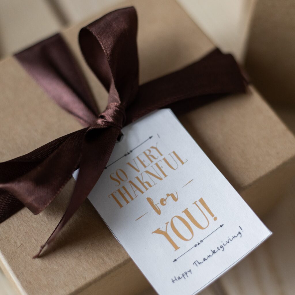 Brown gift box with dark brown bow and card saying "So very thankful for you! Happy Thanksgiving!"