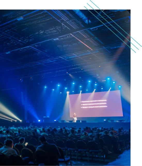Large audience watching a presentation on a lit stage