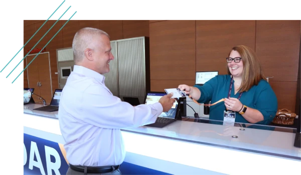 Registration desk staff handing over an attendee badge