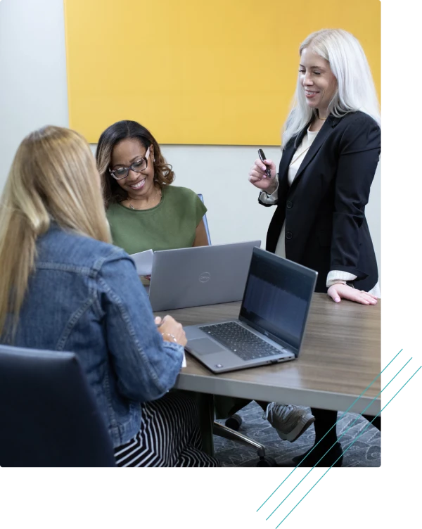 Women in a meeting reviewing work on laptops